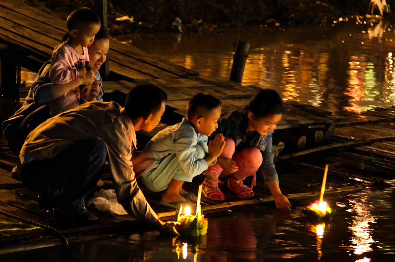 A family float candles in paper boats during the festival of Loi Krathong. Credit: John Shedrick. Licensed under CC BY 2.0